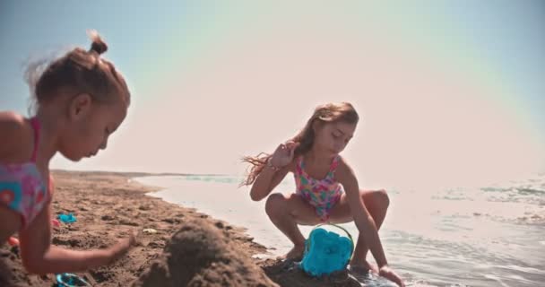 Bambini multietnici adottati che giocano con i giocattoli sulla sabbia della spiaggia — Video Stock