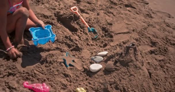 Nuori tyttö leikkii leluja rannalla hiekka kesällä — kuvapankkivideo