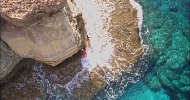 Vista aérea do casal andando sobre a rocha no mar — Vídeo de Stock