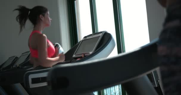 Mujer joven corriendo en la cinta de correr durante el entrenamiento de gimnasio — Vídeos de Stock