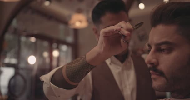 Young old-fashioned stylish barber giving hipster man haircut — Stock Video