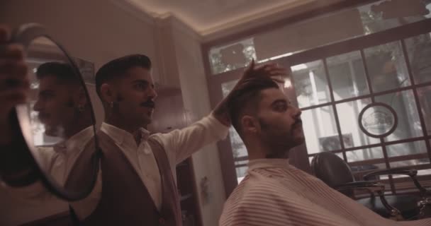 Ung snygg frisör håller spegel och visar man ny frisyr — Stockvideo