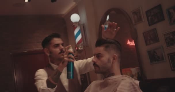 Young stylish hairdresser styling mans hair in old-fashioned barber shop — Stock Video