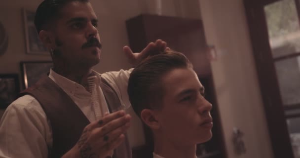 Hipster hairdresser styling young mans hair at old-fashioned barber shop — Stock Video