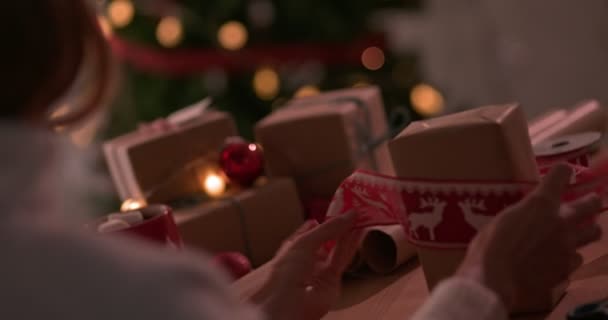 Mulher embrulhando presentes de Natal com fita de férias — Vídeo de Stock