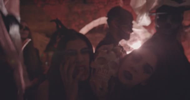 Женщины в готических костюмах на Хэллоуин держат череп на вечеринке — стоковое видео