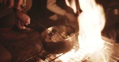Kamp tatilinde kamp ateşinde yemek pişiren adam.