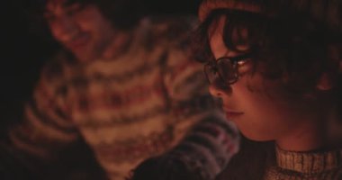 Babasıyla genç bir çocuk kamp ateşinde şekerleme pişiriyor.