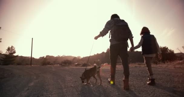 Joven padre e hijo caminando por sendero de montaña con perro — Vídeo de stock