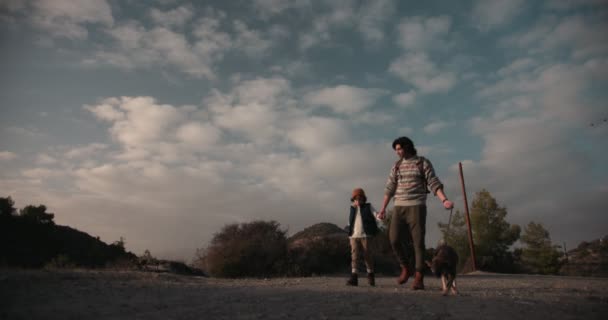 年轻的父亲和儿子与狗在大自然的人行道上散步 — 图库视频影像