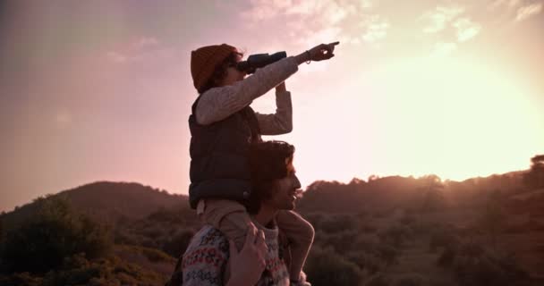 Niño en los hombros de los padres excursionistas usando prismáticos para observar aves — Vídeo de stock