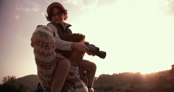 Jeune fils aidant père randonneur avec jumelles au coucher du soleil — Video