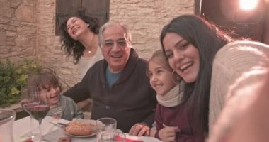 Üç kuşak aile öğle yemeğinde selfie çekiyor.