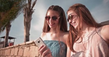 Genç hippi kadınlar sahilde mesaj okurken eğleniyorlar.