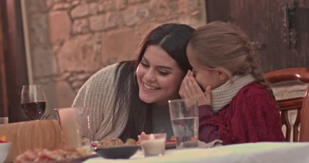 Kleine Tochter flüstert Müttern beim Mittagessen Geheimnisse ins Ohr — Stockvideo