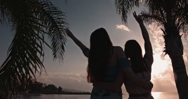 Jonge vrouwen maken vredesteken en kijken naar zonsondergang — Stockvideo