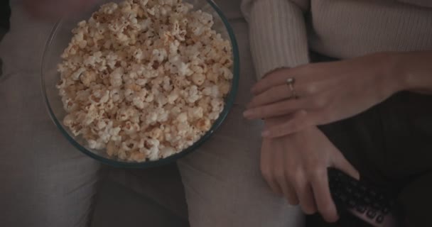 Nahaufnahme eines Paares, das fern sieht und zu Hause Popcorn isst — Stockvideo