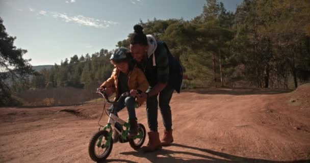Hipster father helping son ride the bike in the countryside — Stock Video