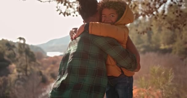 Hipster padre y joven hijo abrazando en la naturaleza — Vídeo de stock