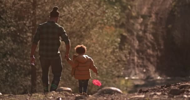 Père et fils descendent la colline en allant pêcher à la rivière — Video