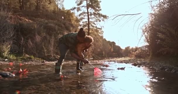 Padre joven enseñando a su hijo a pescar en el río — Vídeo de stock