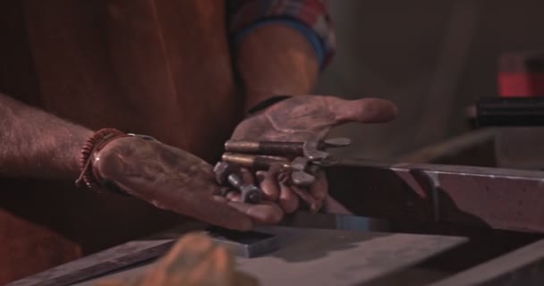 Nahaufnahme eines Mechanikers, der Schrauben in Händen über der Werkbank hält — Stockvideo