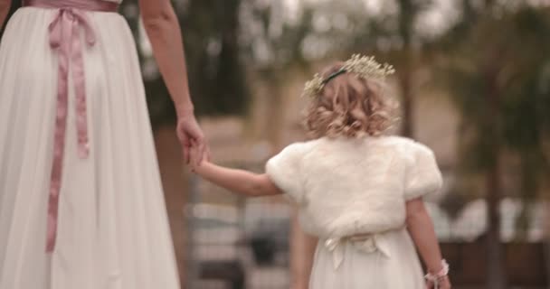 Cute little flower girl holding hands and walking with bride — Stock Video