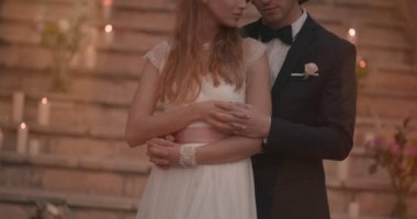 Genç romantik gelin ve damat sarılıyor ve el ele tutuşuyorlar.