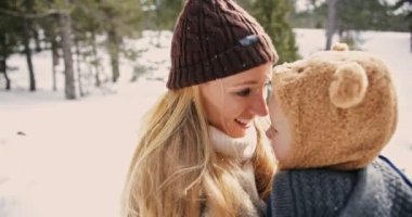 Anne ve küçük çocuk karda birlikte eğleniyorlar.