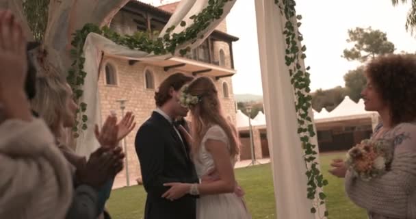 Новоспечена пара цілується на сільському котеджі церемонія весілля з гостями — стокове відео