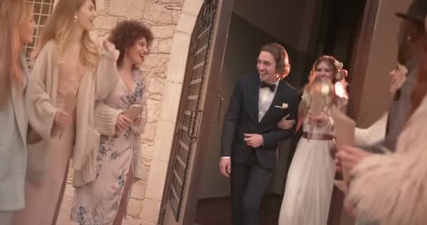 Newlywed couple walking out of church with guests celebrating — Stock Video