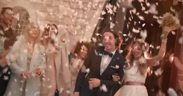Hosté házejí konfety na nevěstu a ženicha opouštějící kostel — Stock video