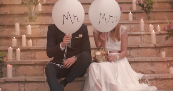 Mariée et marié assis sur des marches de pierre et tenant des ballons — Video