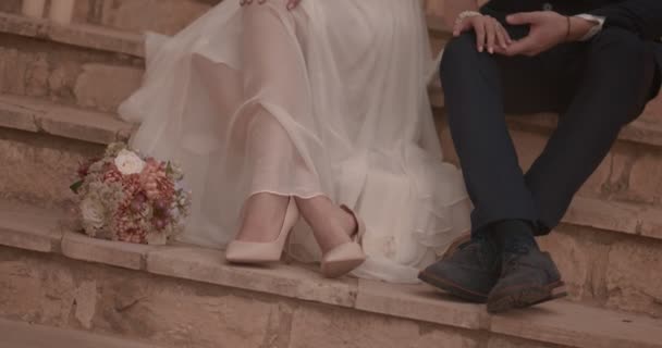 Bride and groom sitting on stone steps and relaxing together — Stock Video