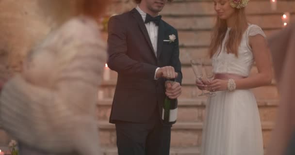Yeni evli gelin ve damat kutlama yapıyor ve şampanya şişesi açıyor. — Stok video