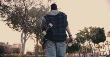 Uzun tahta tutan, kahve içen ve şehirde yürüyen bir adam.