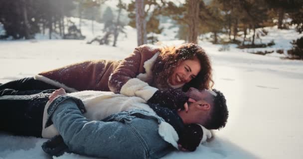 Joven pareja romántica tumbada en la nieve y abrazando — Vídeo de stock