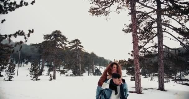 Hipster vänner har kul med piggyback rida i snön — Stockvideo