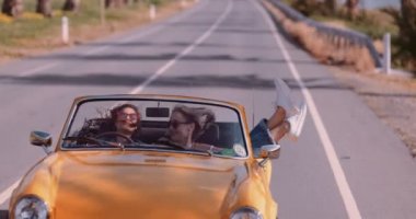 Yolculukta mutlu kadınlar klasik sarı Cabriolet araba kullanıyorlar.