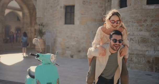 Νέοι τουρίστες ζευγάρι με σκούτερ διασκεδάζοντας με piggyback βόλτα — Αρχείο Βίντεο