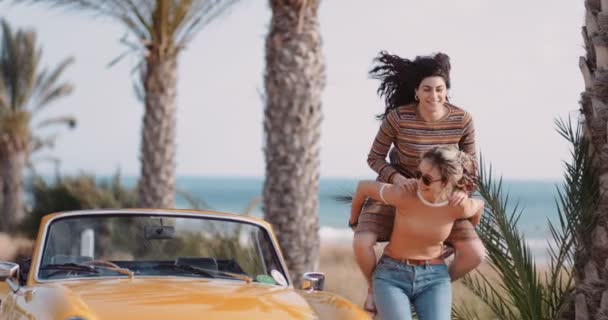 Hipster flickor har kul med piggyback rida på road trip — Stockvideo
