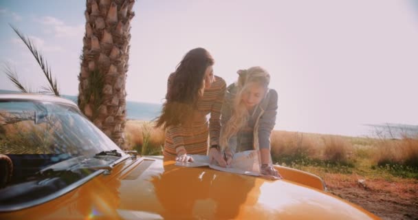 Jeunes hipster femmes lecture carte sur convertible car road trip — Video