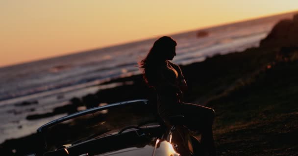 Wanita dengan mobil konversi antik bersantai di pantai saat matahari terbenam — Stok Video