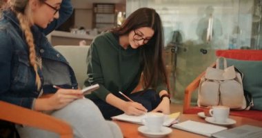 Genç üniversite öğrencileri kafeteryada birlikte okuyorlar.