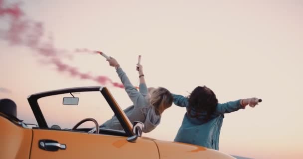 Young women with vintage convertible car celebrating with smoke bombs — Stock Video