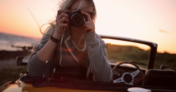 Frau auf Roadtrip sitzt im Cabrio und fotografiert — Stockvideo