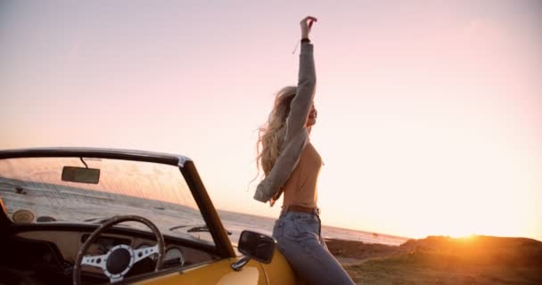 Mulher com carro conversível relaxante junto ao mar ao pôr-do-sol — Vídeo de Stock