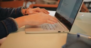 Laptop kullanan ve kafede ödev yapan bir üniversite öğrencisi.