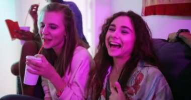 Çok ırklı arkadaşlar evde dinlenip fast food hamburgerleri yiyorlar.