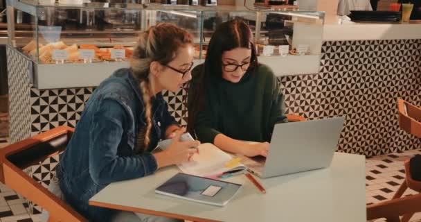 Jóvenes estudiantes universitarios haciendo investigación utilizando portátil en la cafetería urbana — Vídeo de stock